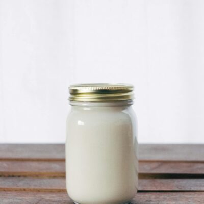 A rustic glass jar filled with creamy yogurt, placed on a wooden table. Ideal for healthy food themes.