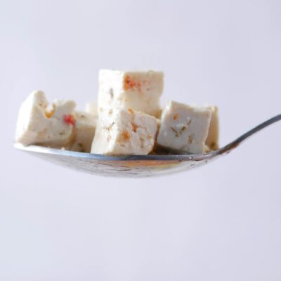 Close-up of cheese cubes on a spoon, showcasing minimalist food photography.