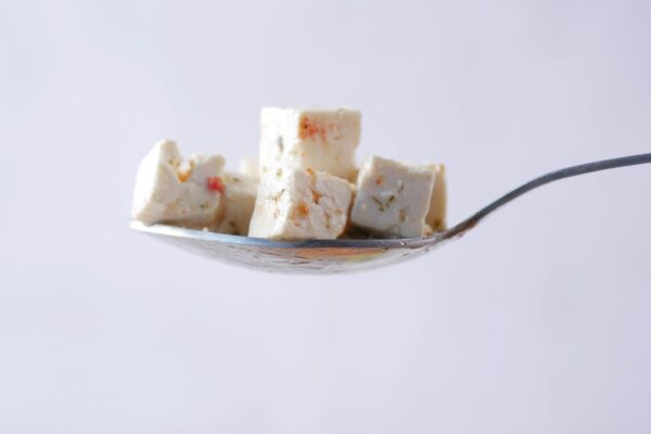 Close-up of cheese cubes on a spoon, showcasing minimalist food photography.