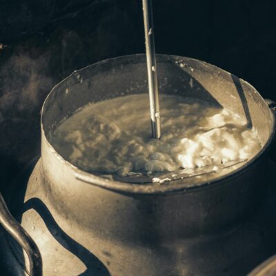 Close-up of creamy milk being churned in a vintage metal container, illustrating traditional dairy methods.