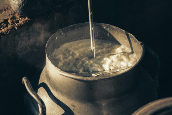 Close-up of creamy milk being churned in a vintage metal container, illustrating traditional dairy methods.