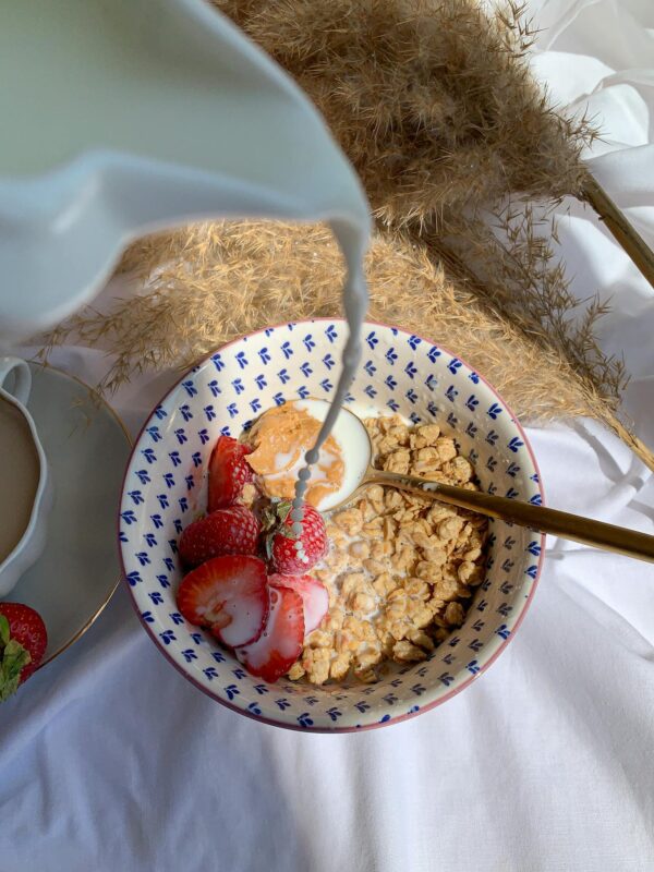 Delicious bowl of granola with fresh strawberries, yogurt, and milk being poured, perfect for a healthy breakfast.