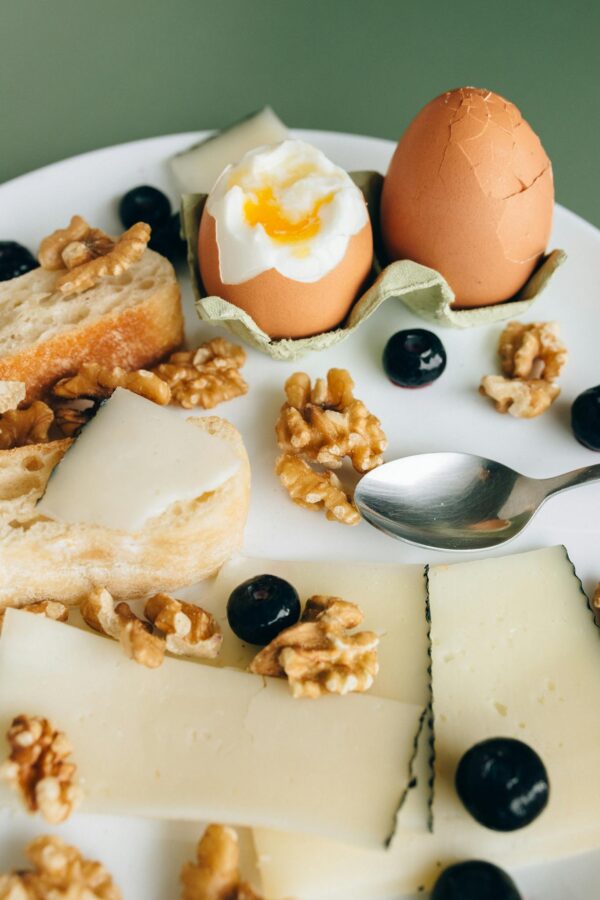 Delicious breakfast plate featuring boiled eggs, walnuts, cheese, and fresh bread.