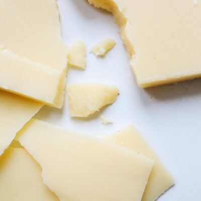 High-quality close-up image of cracked Parmesan cheese pieces on a clean white surface.